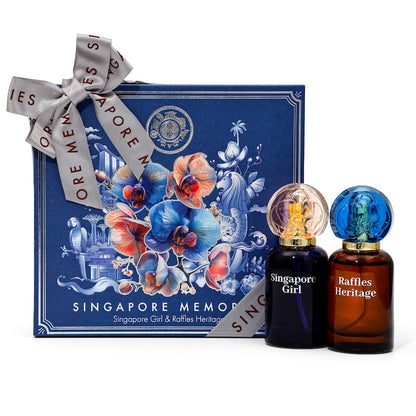 A dual gift pack of Singapore Girl and Raffles' Heritage perfumes, presented in a blue gift box with floral illustrations and a ribbon. The set includes two perfume bottles with decorative caps.
