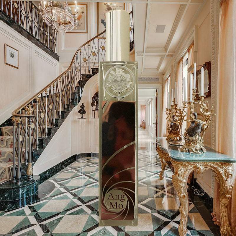 Beautiful metal brown Angmo room fragrance a tall, slender crystal bottle with a spray nozzle, set in an elegant rich house as background