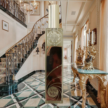Beautiful metal brown Angmo room fragrance a tall, slender crystal bottle with a spray nozzle, set in an elegant rich house as background