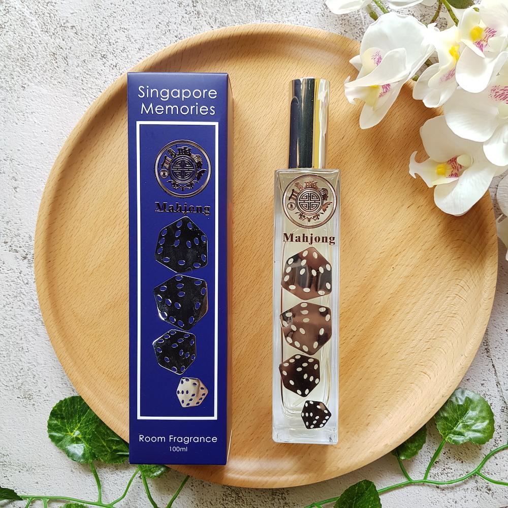 mahjong fragrance bottle with silver dice decoration, next to a blue gift box and on top of wooden circular plate