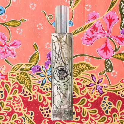 Nyonya perfume bottle with silver cap and silver chain design in front of pink batik printed peranakan fabric