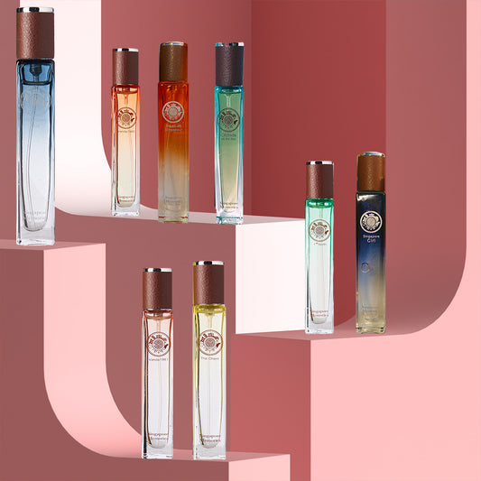 A collection of perfume bottles with a gradient color design, displayed against a pink backdrop.