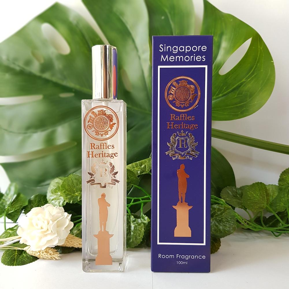 raffles perfume bottle next to a blue gift box in front of green leaves and white flower
