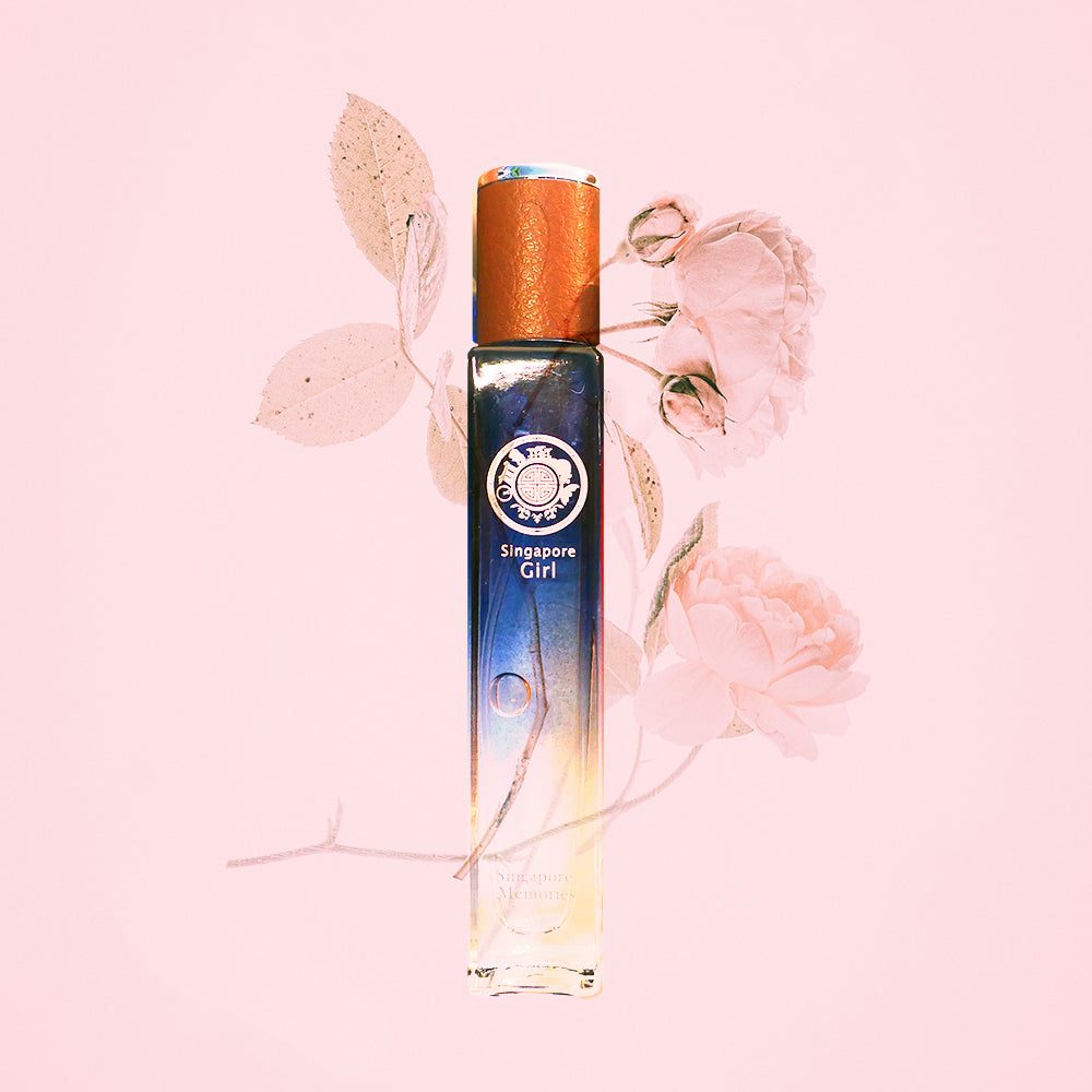 A bottle of 'Singapore Girl' perfume with a blue and white label, featuring a lotus flower and leaves on a pink background.