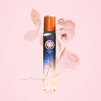 A bottle of 'Singapore Girl' perfume with a blue and white label, featuring a lotus flower and leaves on a pink background.