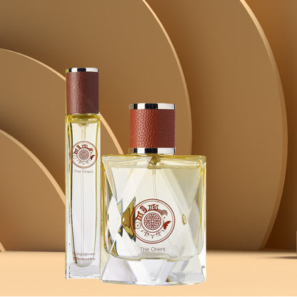 Two bottles of perfume, one larger than the other, with a beige liquid inside. Both have brown caps and are displayed against a beige background with circular patterns.