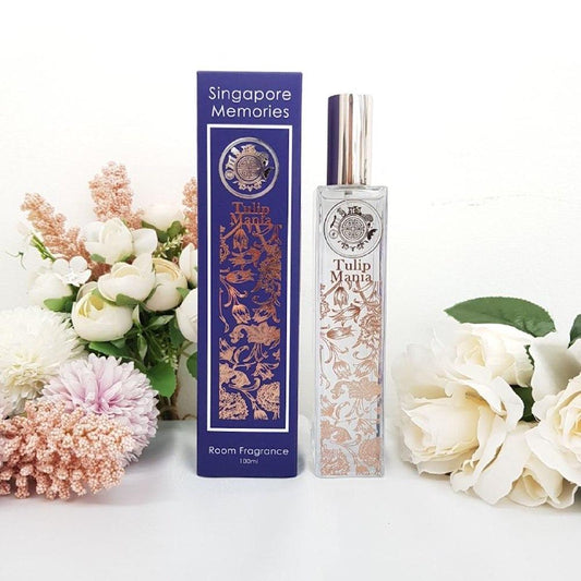 Tulip Mania room fragrance in elegant glass  bottle with metal embellishments, next to a blue gift box and in front of white flowers and background