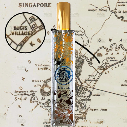 A bottle of fragrance with a map of Singapore in the background, highlighting the 'Bugis Village' area. The fragrance bottle has a clear liquid, gold accents, and a gold cap.