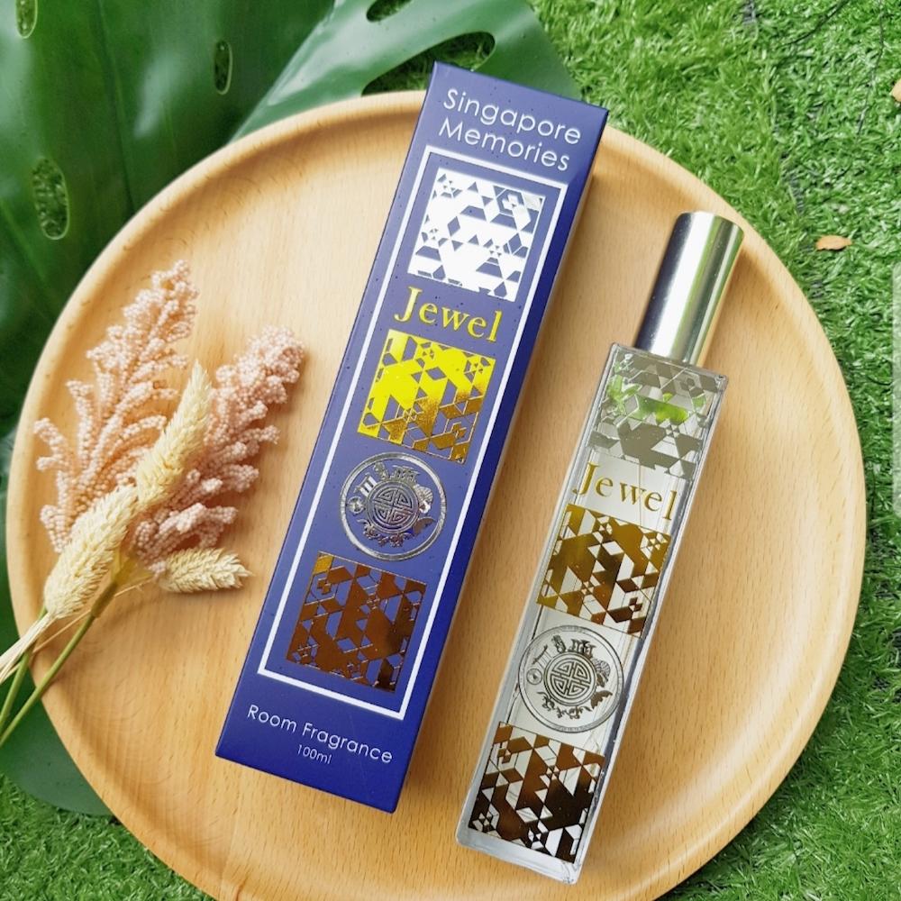 jewel scent bottle next to a blue gift box on top of a wooden tray and grass