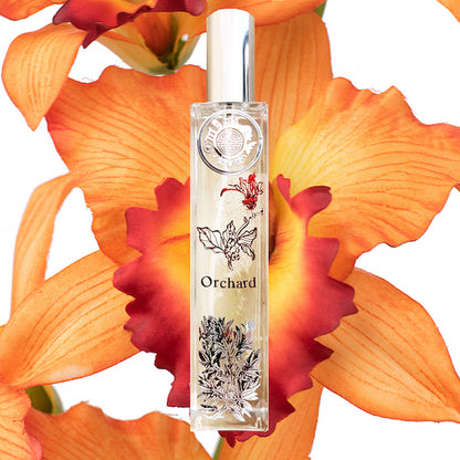 Orchard orchids room fragrance with floral motif on crystal bottle and silver cap. Background is bright orange orchid flower