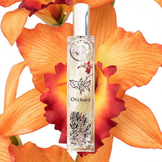 Orchard orchids room fragrance with floral motif on crystal bottle and silver cap. Background is bright orange orchid flower