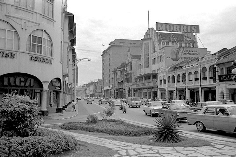 an old picture of singapore with European looking buildings, cars and few corporate hoarding stating Morris and British council