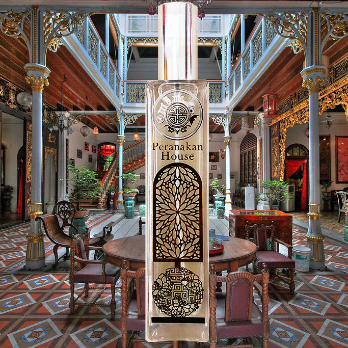 A tall, ornate bottle of Peranakan fragrance, with intricate carvings and designs, displayed in a beautifully decorated room.