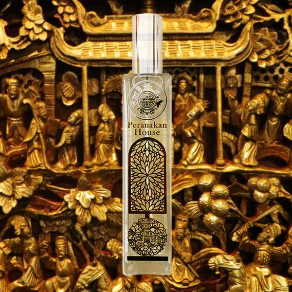 Peranakan room fragrance in gold and glass bottle in front of luxurious gold wooden carving