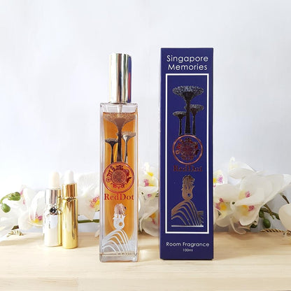 Red dot scent bottle next to blue gift box and 2 essential oil bottle, with white orchids in background 