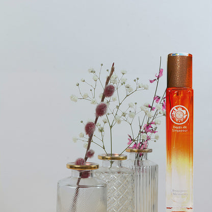 Reves De Singapour, singapore memories, revival of old perfume from 1960 in orange bottle with dry leaves in front in decorated glass reed diffuser bottles