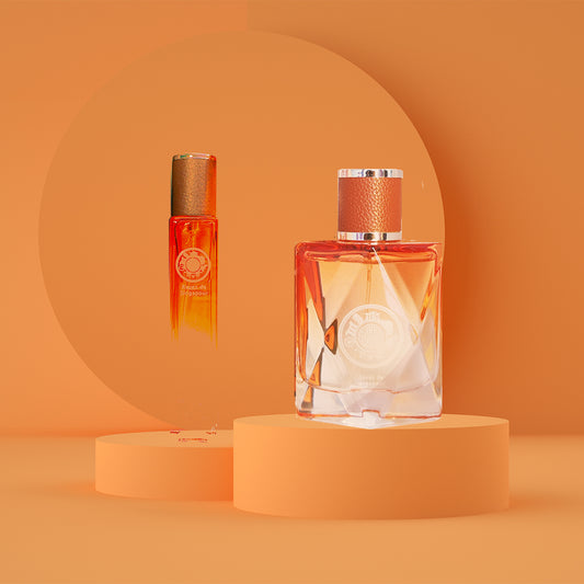 A perfume bottle and box, with the bottle having a gold and orange label, placed on orange-colored pedestals against an orange background.
