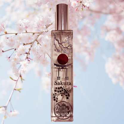 A clear glass bottle with a silver cap and a red spherical object inside, labeled 'SAKURA', set against a background of pink cherry blossoms.