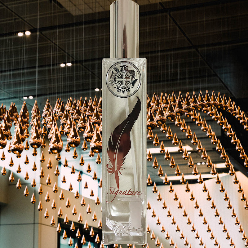 Signature singapore room fragrance bottle in front of metal water drops
