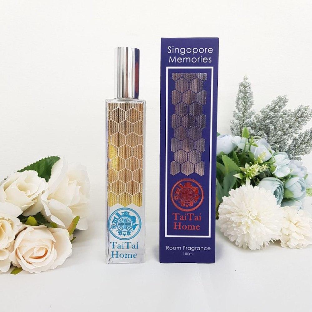 tai tai room fragrance in glass bottle with elegant geometrical design next to a blue gift box on white background with white flowers
